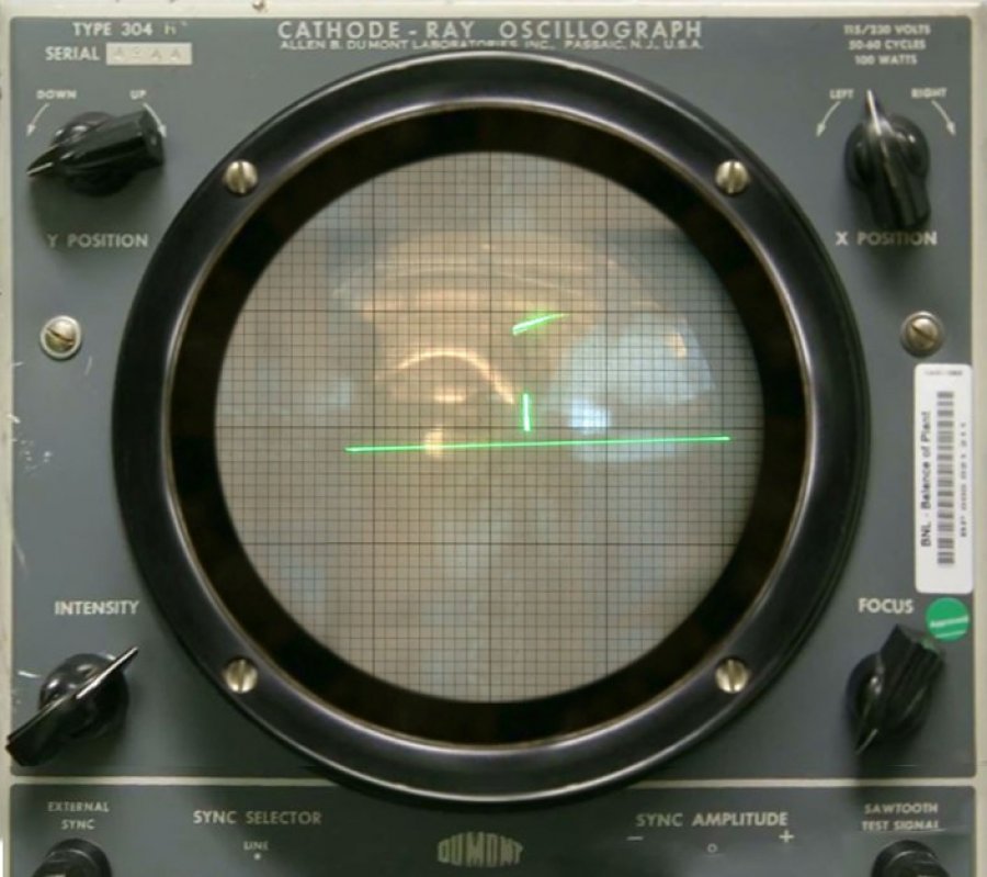 Ein technisches Gerät mit einem runden Bildschirm. Auf dem Bildschirm ist ein grüner Punkt, der von rechts nach links ein Spielfeld fliegt.