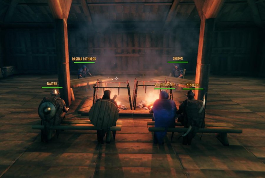 Sechs Krieger sitzen in einem Langhaus um ein Herdfeuer.